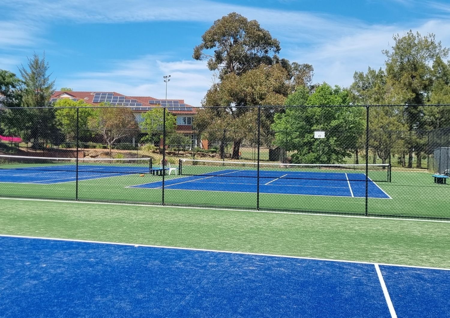 Blue and green tennis courts with benches and chairs