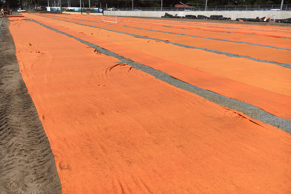 Orange fabric laid over field of play eathworks