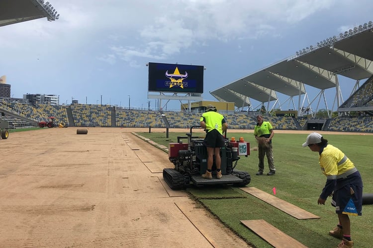 workers installing natural turf using big machinery on elite sport stadium